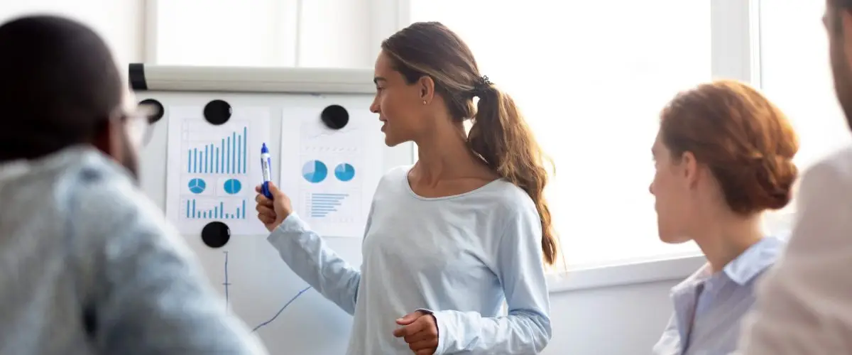 Woman presenting charts on a flip chart to a group during a business meeting